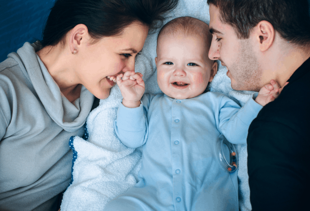 mom and dad cuddling with smiling baby