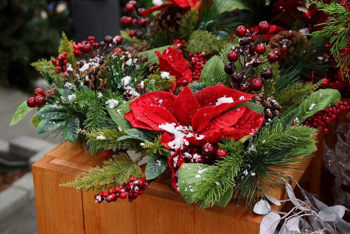 Bright beautiful New Year's decor in a basket of green coniferous branches, red leaves and berries under white snow on the table