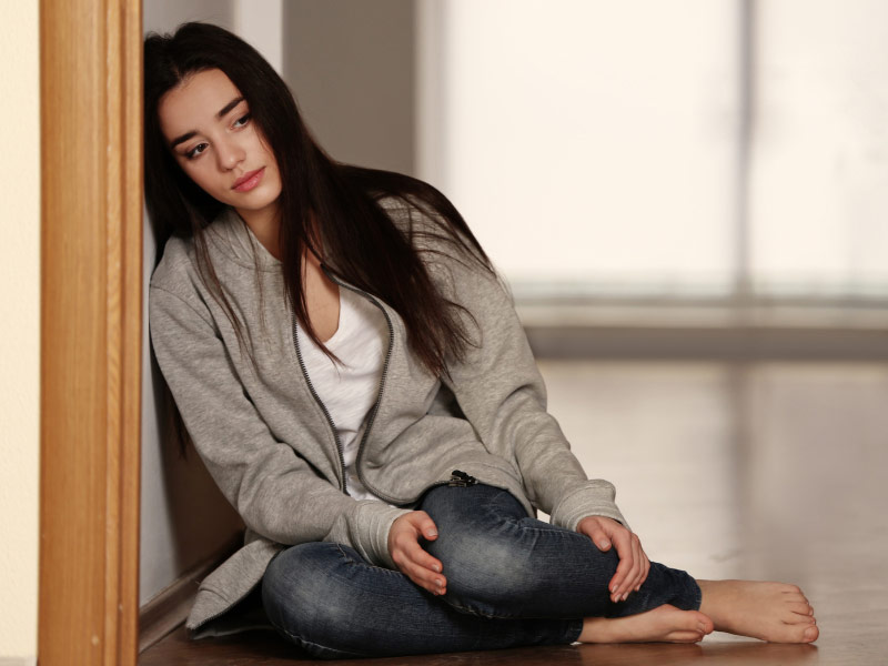 a woman sitting on the floor with a sad expression on her face