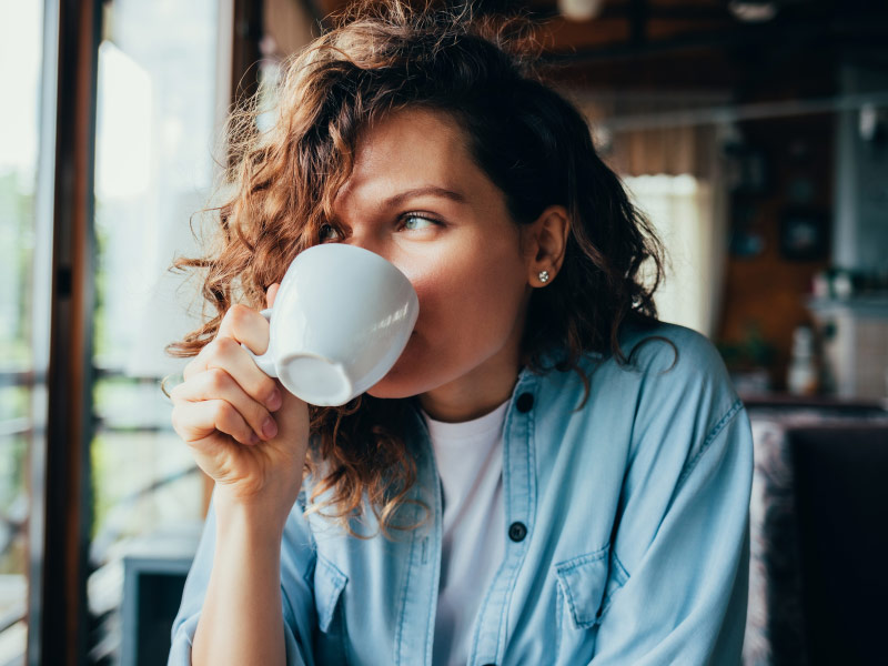 a woman drinking coffee from a white mug