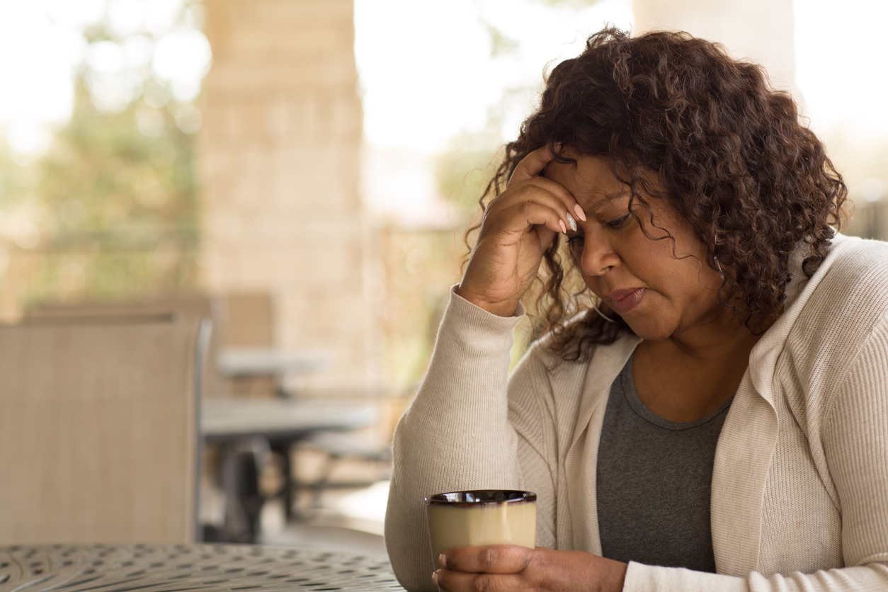 a woman sitting at a table with her hand on her forehead